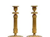 pair of antique brass candlesticks on pedestals on a white background