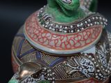 a green and red vase with a snake on it