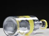 yellow tape wrapped around a glass bottle on a white surface