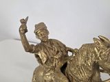 brass figurine of a man riding a horse with a hat on his head