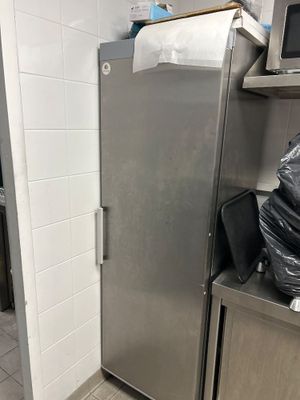 a stainless steel refrigerator in a kitchen with a trash bag on the counter