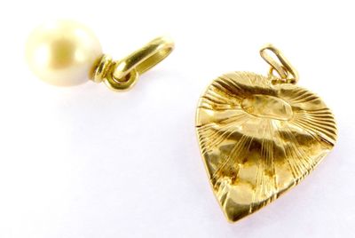 a gold heart charm with a pearl on it