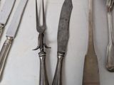 a lot of silverware on a table with knives and spoons