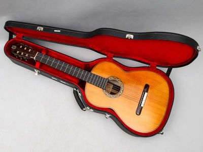 une guitare dans un étui, posée sur une surface blanche