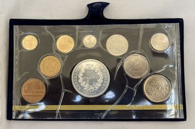 un assortiment de pièces de monnaie dans un étui en plastique posé sur une surface blanche