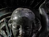 a statue of a child holding a fan on a pedestal