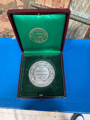 a silver medal in a green box on a blue table