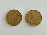 a pair of two gold coins sitting on top of a white surface