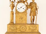 a gold clock with a man holding a bird and a vase