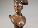 bronze bust of a woman with a hat on her head
