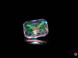 un gros plan d'un diamant vert et violet sur une surface noire