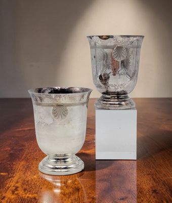 deux vases en argent posés sur une table en bois dotée d'un socle blanc