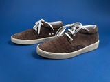 brown sued sneakers with white laces on a blue background