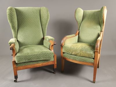 une paire de fauteuils à oreilles rembourrés verts montés sur roulettes