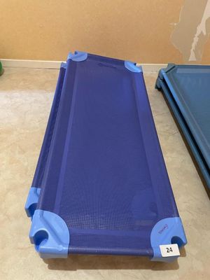 a blue cot that is on the floor next to a blue cot
