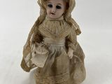 une petite poupée qui porte une robe et un chapeau
