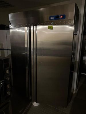 un grand réfrigérateur en inox dans une cuisine dotée de nombreux plans de travail