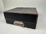 an old black suitcase sitting on a white surface
