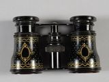 two black and gold binoculars sitting on a white surface