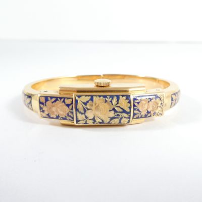 un gros plan d'un bracelet doré et bleu posé sur une surface blanche