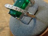 an image of a ring with a green stone and diamonds on it
