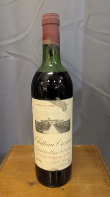 an old bottle of wine sitting on top of a wooden table