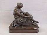 statue en bronze représentant une femme assise sur un socle en bois, accompagnée d'un chien