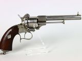 un vieux revolver avec une poignée en bois sur une surface blanche