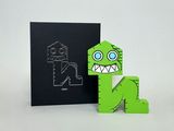a green paper toy that is next to a black card