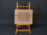 a wooden easel with a painting on it against a black background