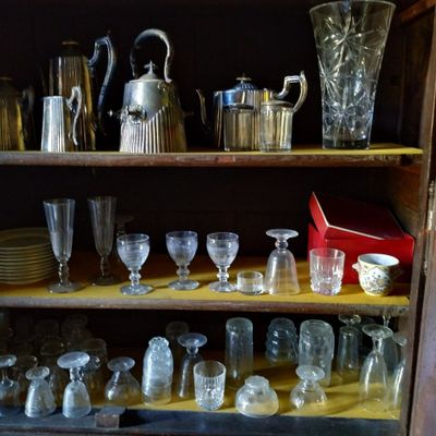 de nombreux verres et pichets posés sur une étagère dans un placard