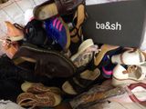 a pile of shoes and a laptop on a bed