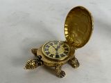 a small gold turtle with a clock in it ' s shell
