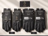 Quatre paires de gants en cuir noir sont exposées dans un magasin