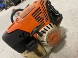 an orange and black chainsaw sitting on the ground in a garage