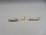 three silver figurines of a dog, a cat, and a dog