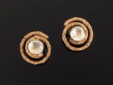 a pair of gold and pearl earrings on a black surface