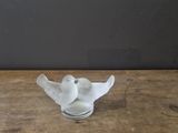 a small glass bird sitting on a wooden table