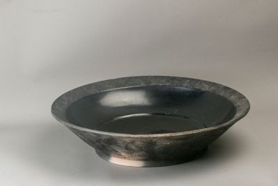 un bol noir posé sur une table blanche, sur fond blanc
