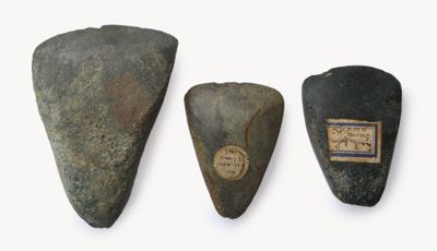 Trois types différents d'outils en pierre sont exposés sur une surface blanche