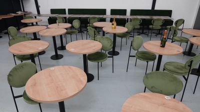 de nombreuses tables et chaises dans une pièce, avec une bouteille posée sur la table