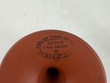 a brown vase with a tag on it sitting on a table