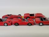 several red toy cars are lined up in a row on a white surface