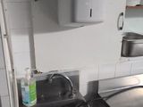 a sink in the middle of a kitchen with a soap dispenser on the wall