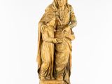 a wooden statue of a woman sitting on a stool