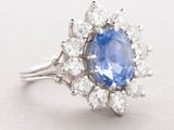 a close up of a ring with a blue sapphire surrounded by white diamonds