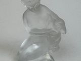 a glass figurine of a boy sitting on top of a table