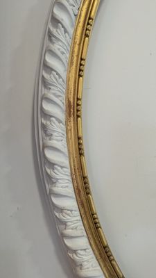 un miroir ovale doré et blanc accroché au mur