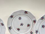 three white plates with floral designs on them sitting on a table