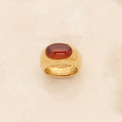 two gold rings with a red stone on top of a white surface